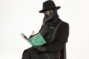 Portrait of a plague doctor from Medieval era sitting and taking notes in a book with a feather. high-quality costume. Isolated on a white background. epidemic and pandemic concept.