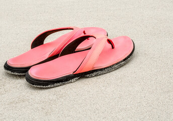 Pair of pink flip flops on the sandy beach