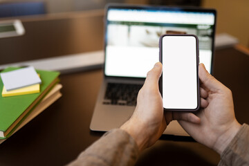 Student holding mobile phone with a blank screen, online learning, preparing for exam. Male text message, checking mail, online communication. Selective focus, Mockup
