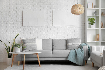 Grey sofas with cushions and houseplant on table in interior of living room