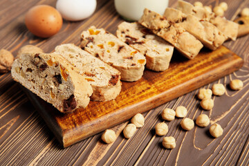 Board with delicious biscotti cookies and hazelnuts on brown wooden background