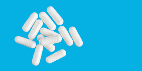 White therapeutic capsules, vitamin pills or drugs for treatment on blue background, medicine and healthcare concept, top view