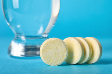 Soluble tablets and glass of water on blue background