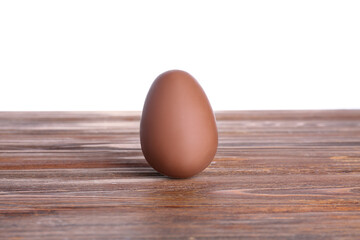 Chocolate Easter egg on wooden table against white background