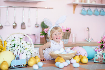 Fototapeta na wymiar Easter at home. little girl with bunny ears in kitchen decorated for celebrates a religious holiday. Pastel colors