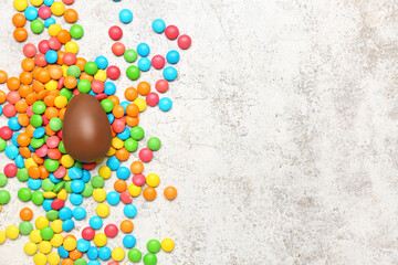 Fototapeta na wymiar Chocolate Easter egg and candies on grey grunge background