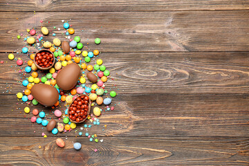 Chocolate Easter eggs and candies on brown wooden background