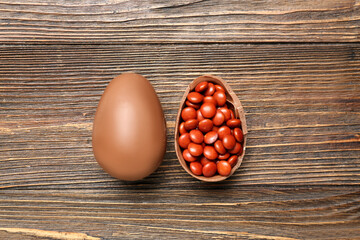 Chocolate Easter eggs with candies on brown wooden background