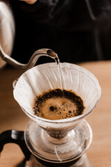 Close-up pour over filter with ground coffee in the funnel in focus. Drip filter coffee brewing....