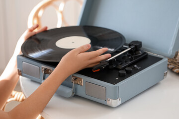 Obraz premium Little girl with vinyl disc and record player on table in kitchen, closeup