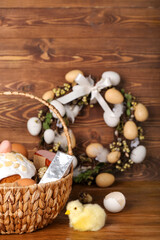 Basket with Easter eggs and cake on wooden background