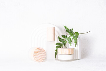 Eco friendly natural cosmetic products such as cream, loton, serum or balm on white stone background with clay geometric decorations and fern leaves. Skin care concept.