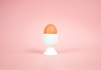 Eegg in egg cup on a pink background. Easter concept.
