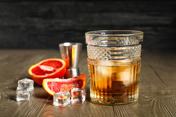 Glass of rum with ice and Sicilian orange on wooden table