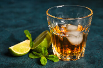 Glass of rum with ice, mint and lime on table
