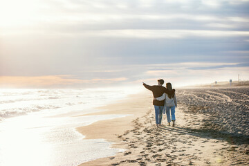 Beautiful young couple in love walking together in a cold winter day on the beach.