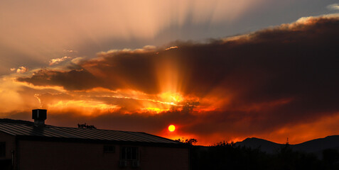 A fire in the sky is burning above a shingle of a house among the mountains