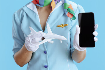 Modern air hostess woman on blue showing smartphone blank screen