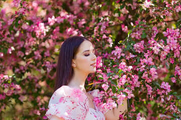Close up of pretty girl with long hair,under pink blooming apple trees