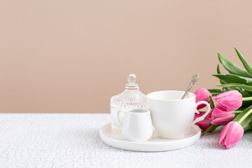 Ceramic tea-set with cup and milk jug on the table. Neutral colors. Place for text.  Simple coffee-set for  menu. 
