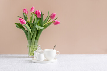 Ceramic whites tea-set, cup and milk jug on the table with flowers . Place for text. Backdrop for tea branding or menu. 