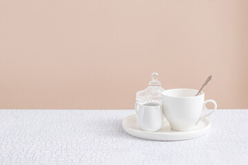 Ceramic saucer, cup and milk jug on the table. Place for text. Backdrop for tea product or menu 