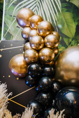 Background, texture of round black, golden balloons on the photo zone against the background of the wall. Photography, holiday, birthday, wedding.