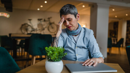 One senior woman sit at cafe gray short hair overworked have headache