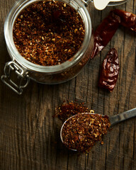 Roasted dry chili pepper powder in jar. Dried chilli on background. Top view.