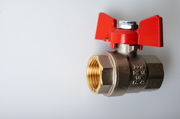 brass metal water faucet with red valve, different angle isolated on light background close up, plumbing connection