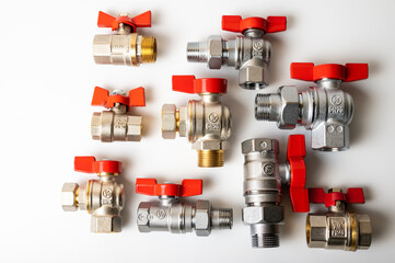brass, metal water faucets with red valve, different, isolated on light background close-up, plumbing connection 