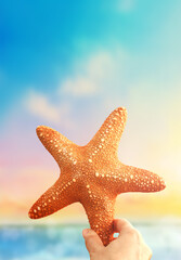 Fototapeta na wymiar Hand holding starfish with tropical summer beach island, relaxing vacation summer blue sea concept.