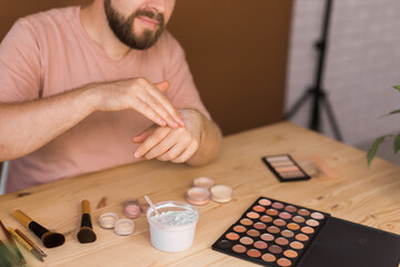 Male beauty blogger testing cream and recording a video lesson his with mobile phone close-up- vlog, diversity and video blog concept