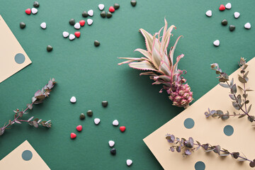 Pineapple, Eucalyptus Twigs in a Flat Lay on Green Paper With heart-shaped candy, natural low...
