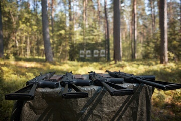 Weapons on the table in front of the targets hung in the forest.