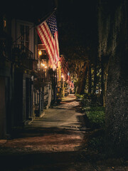 View down old brick-paved street of Savannah, Georgia at night illuminated by gas lamps with a line...