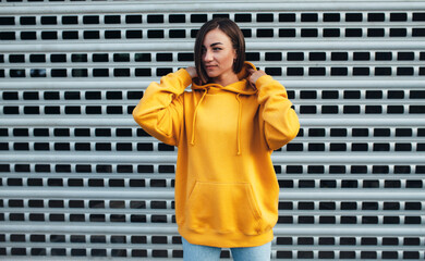 Handsome young female wearing yellow blank hoodie with space for your logo or design. Mockup for...
