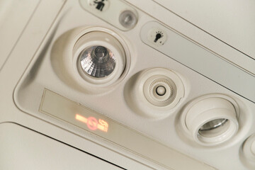 Control panel of lights and air-conditioning system on the ceiling above the passenger seat in the cabin of an airplane