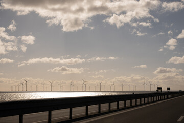 Naklejka premium Windpark Fryslân offshore from Afsluitdijk highway. Dutch wind turbine farm generating clean sustainable renewable energy for Holland on clear sunny day. Netherlands eco power at sea water IJsselmeer