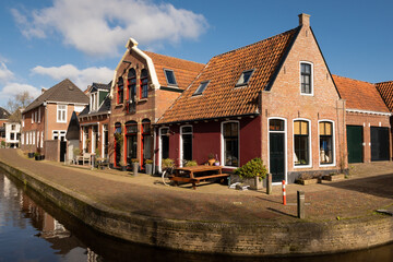 idyllic residences in Dokkum friesland in the Netherlands. pretty canal side street houses with traditional Dutch architecture on corner of Wortelhaven Holland on a sunny day