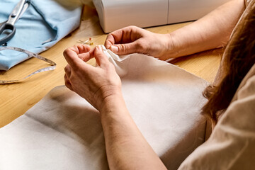 Seamstress basting and sewing in a small studio. Sartorial clothes. Fashion studio, tailoring,...