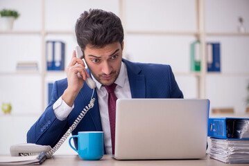 Young male employee speaking by phone in the office