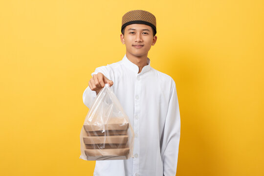 Young handsome asian muslim man giving alms or charity standing over orange background. happy ramadan and eid al-fitr.