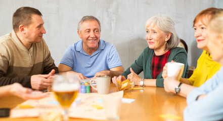 Group of happy mature people playing board game