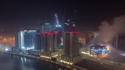 Fototapeta na wymiar Buildings are covered in thick layer of fog in Business Bay night timelapse.
