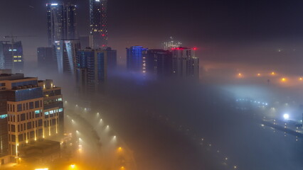 Buildings are covered in thick layer of fog in Business Bay night timelapse.