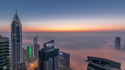 Rare early morning winter fog above the Dubai Marina skyline and skyscrapers lighted by street lights aerial night to day timelapse. - obrazy, fototapety, plakaty