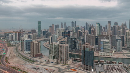 Naklejka na ściany i meble Skyline with modern architecture of Dubai business bay towers night to day timelapse. Aerial view