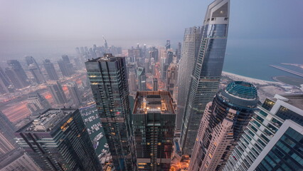 Skyline panoramic view of Dubai Marina showing canal surrounded by skyscrapers along shoreline night to day timelapse. DUBAI, UAE