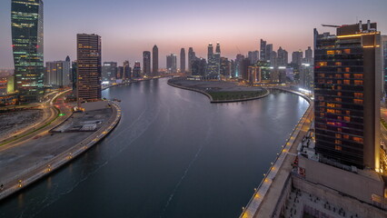 Fototapeta premium Cityscape of skyscrapers in Dubai Business Bay with water canal aerial day to night timelapse